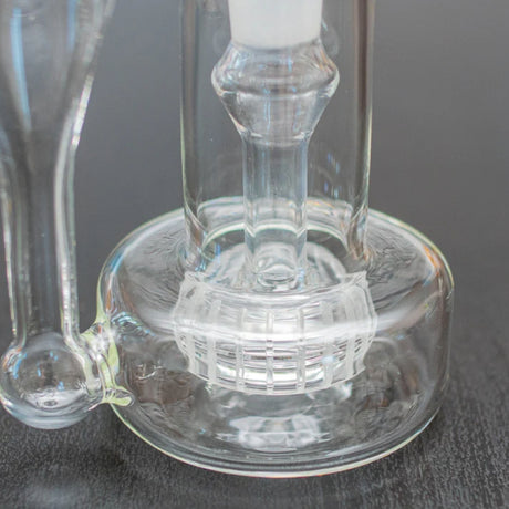 close up image of the percolator of the sneaky pete sidepiece glass rig sat on grey surface